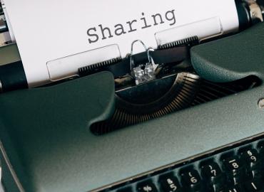 Paper in typewriter with the word &amp;quot;sharing&amp;quot;