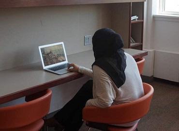A woman sits at a table with a laptop